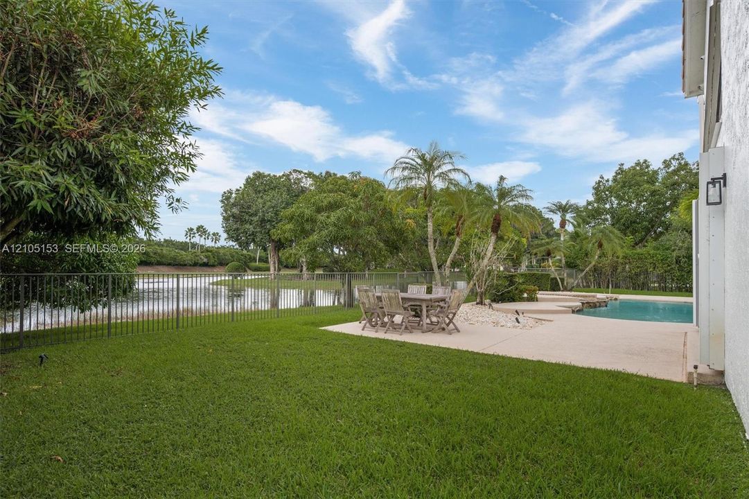 Expansive green lawn with a black metal fence