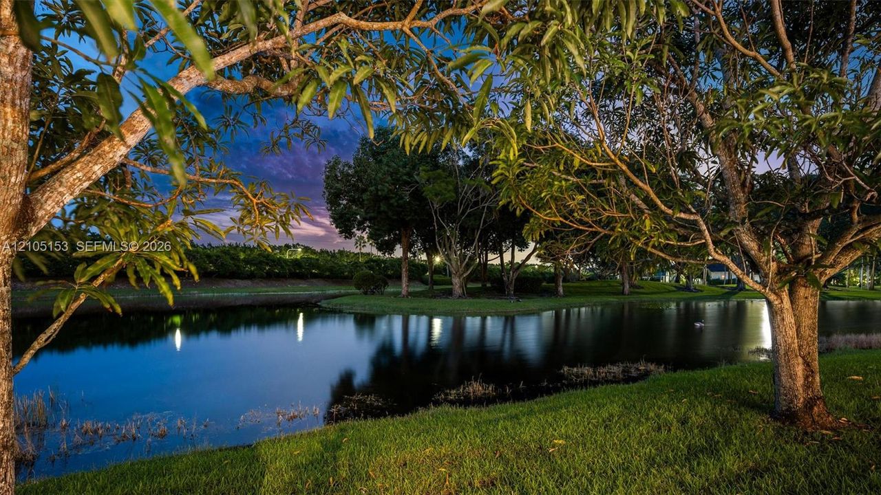 Lush landscaping with mature trees, verdant grass, and a tranquil pond