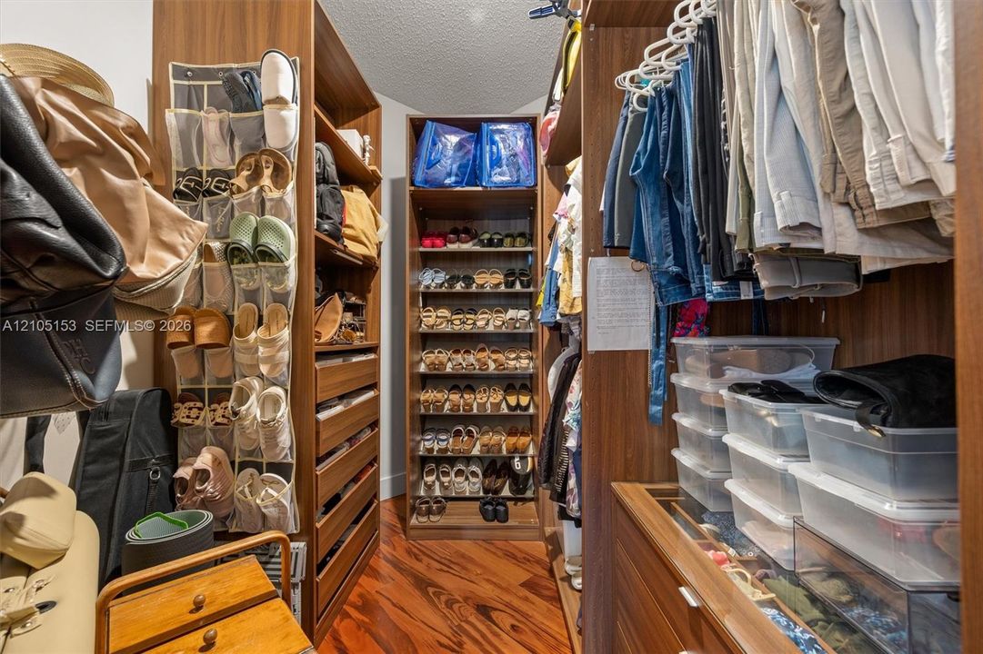 Custom closet system featuring wood-finish cabinetry, integrated shelving, and hanging rods