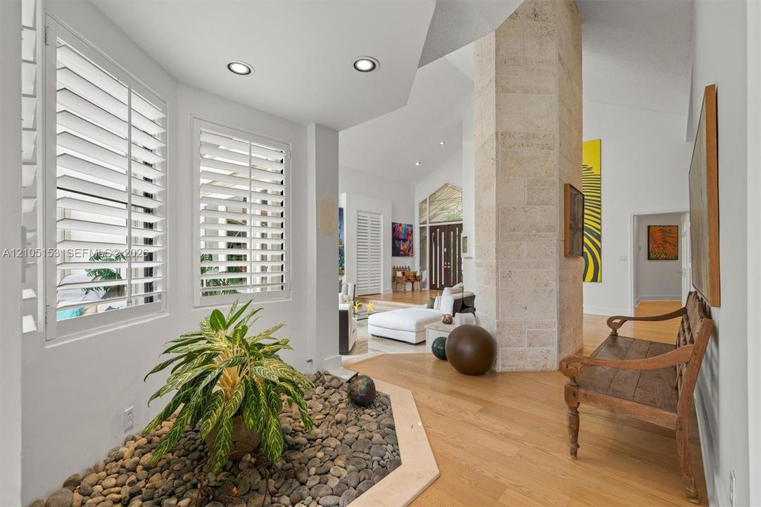 Vaulted ceilings, plank wood-finish flooring, recessed lighting, and a stone-clad architectural column
