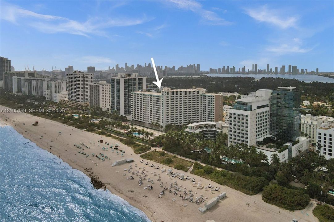 Aerial perspective showcasing a high-rise building with a cityscape background and adjacent beachfront