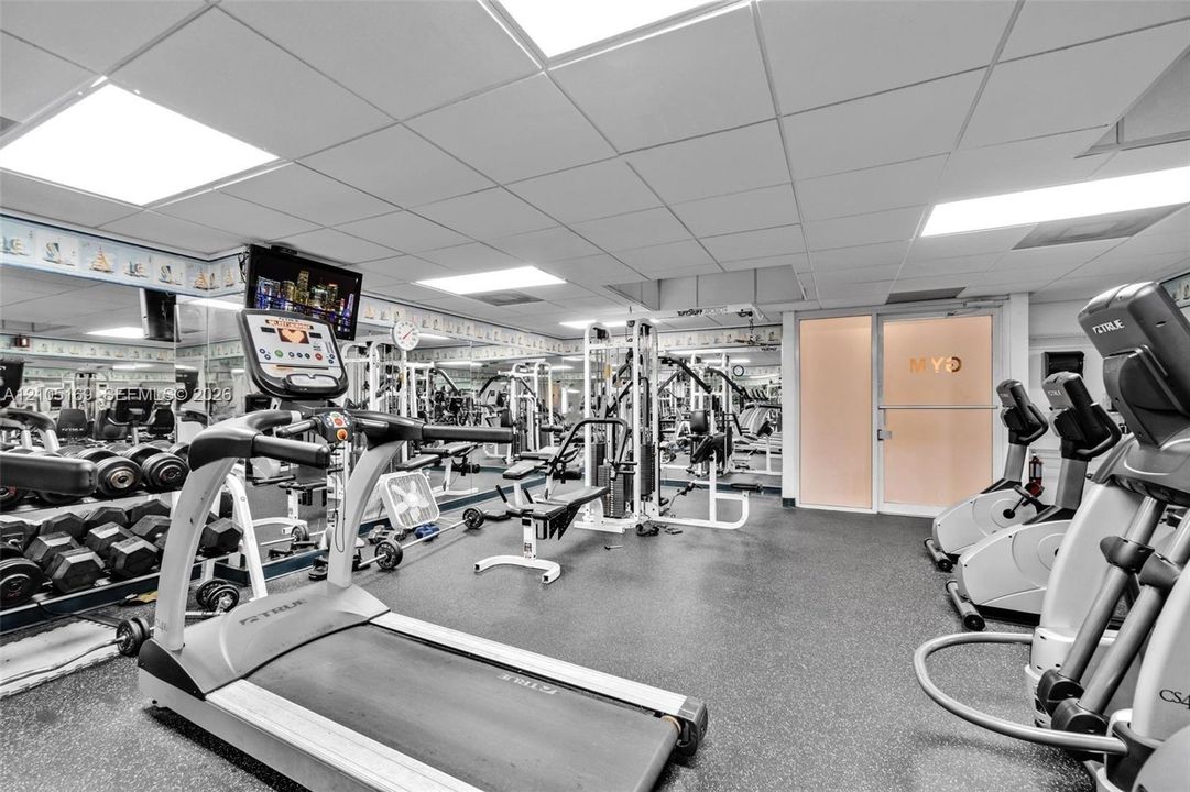 Dedicated fitness facility featuring rubber flooring, mirrored walls, and recessed lighting
