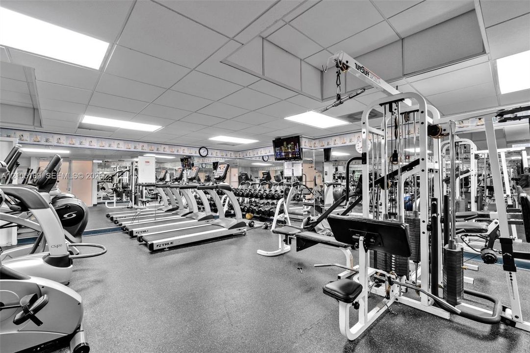 Fitness center featuring extensive cardio equipment, strength training machines, free weights, and resilient flooring