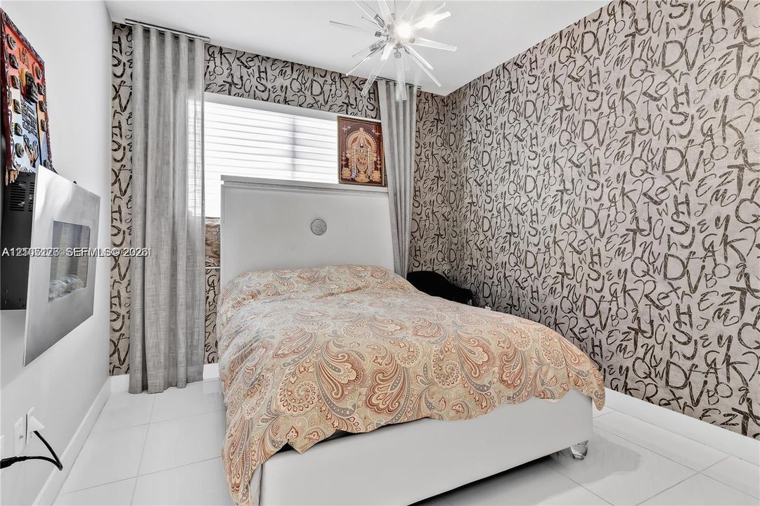 Room featuring large-format tile flooring, a wall-mounted electric fireplace, floor-to-ceiling drapery, and a contemporary multi-arm chandelier