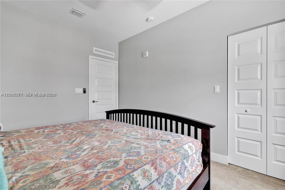 Neutral-toned walls, high ceilings, carpeted flooring, four-panel interior door, and dual-panel closet doors