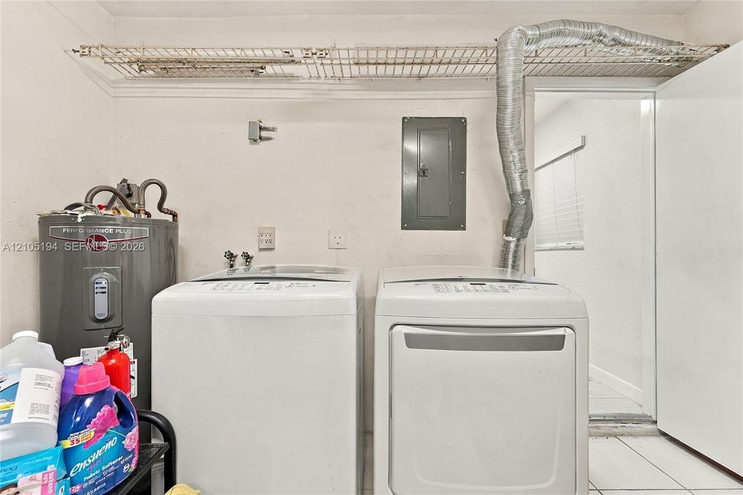 Utility area featuring a water heater, dedicated laundry hookups, integrated circuit breaker panel, and overhead wire shelving