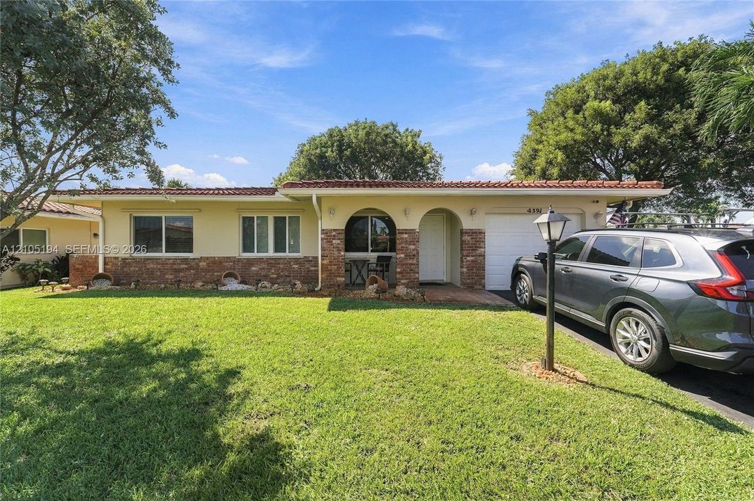 Single-story exterior featuring a textured stucco facade, decorative stone accents, arched entryway, and tile roof