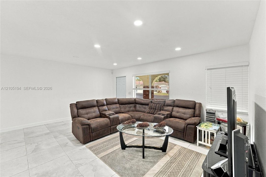 Large-format tile flooring, recessed ceiling lighting, and horizontal window blinds