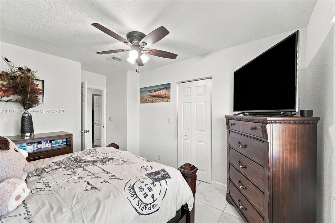 Room featuring white tile flooring, a multi-blade ceiling fan with integrated lighting, and a bi-fold closet door
