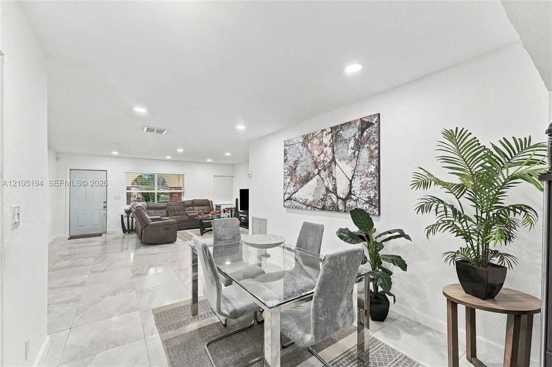 Neutral-toned stone-finish flooring and recessed lighting throughout an open-concept interior featuring smooth wall finishes