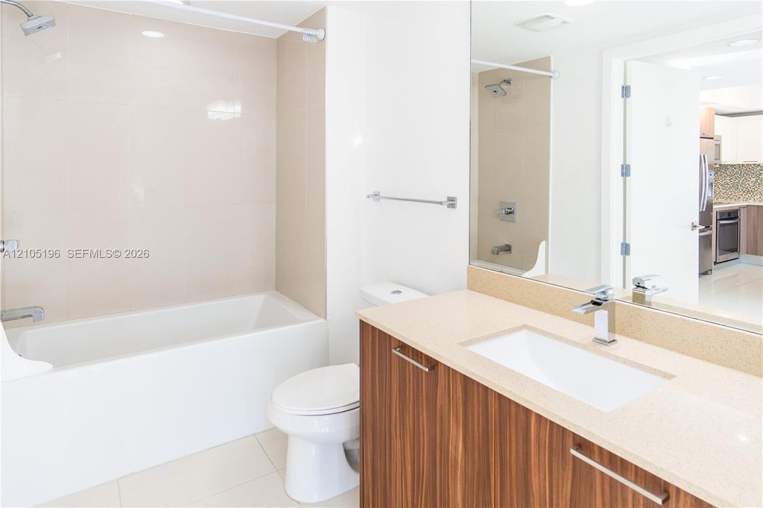 Bathroom featuring a wood-finish vanity with a single basin sink and a light-colored countertop