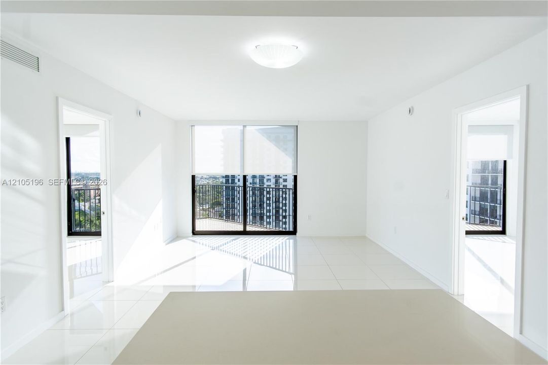 White tile flooring, overhead flush mount lighting, sliding glass door with balcony access, and ample natural light