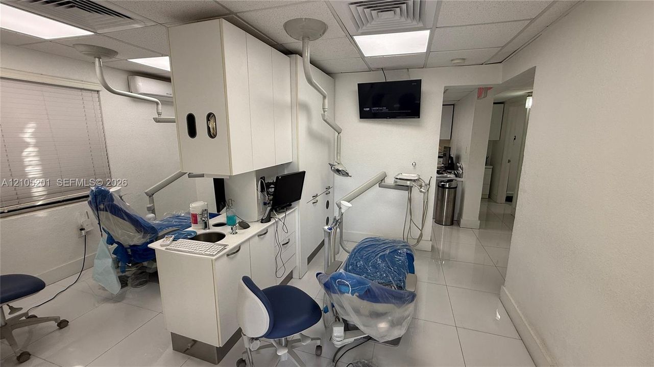 White tile flooring, built-in cabinetry, window with horizontal blinds, integrated lighting, and wall-mounted display