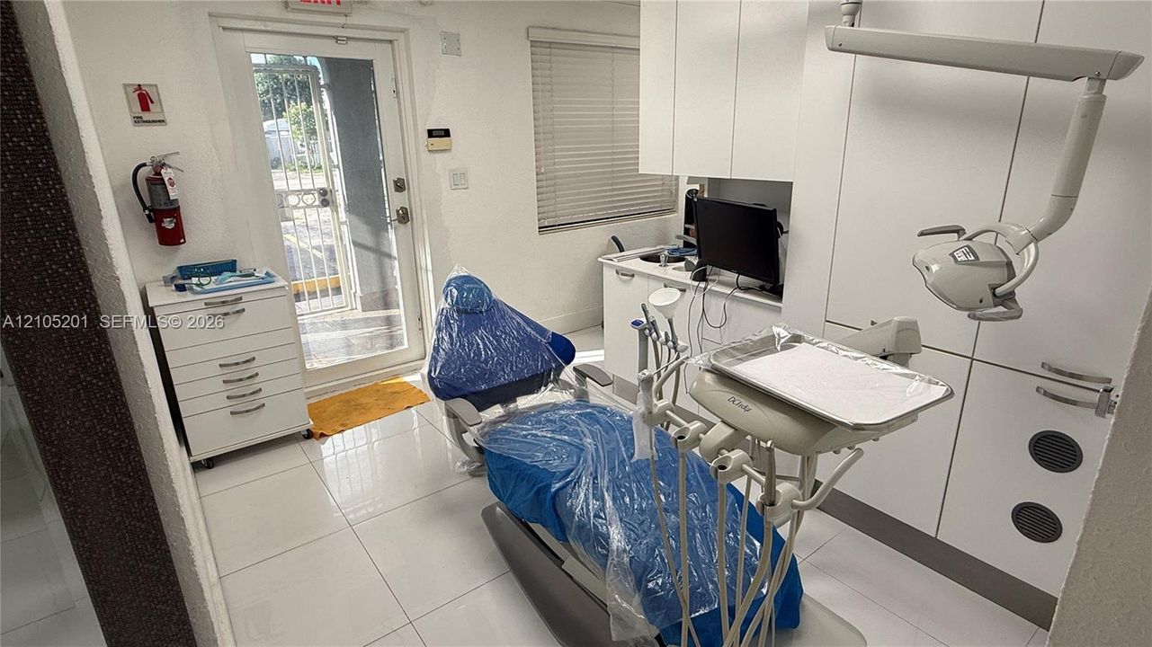 White tiled flooring, white cabinetry, and a door with a security gate