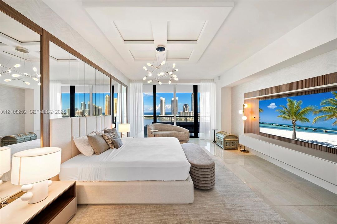 Coffered ceiling with integrated light fixture, mirrored wall panels, built-in media console with wood-slat detailing, polished tile flooring, and floor-to-ceiling windows