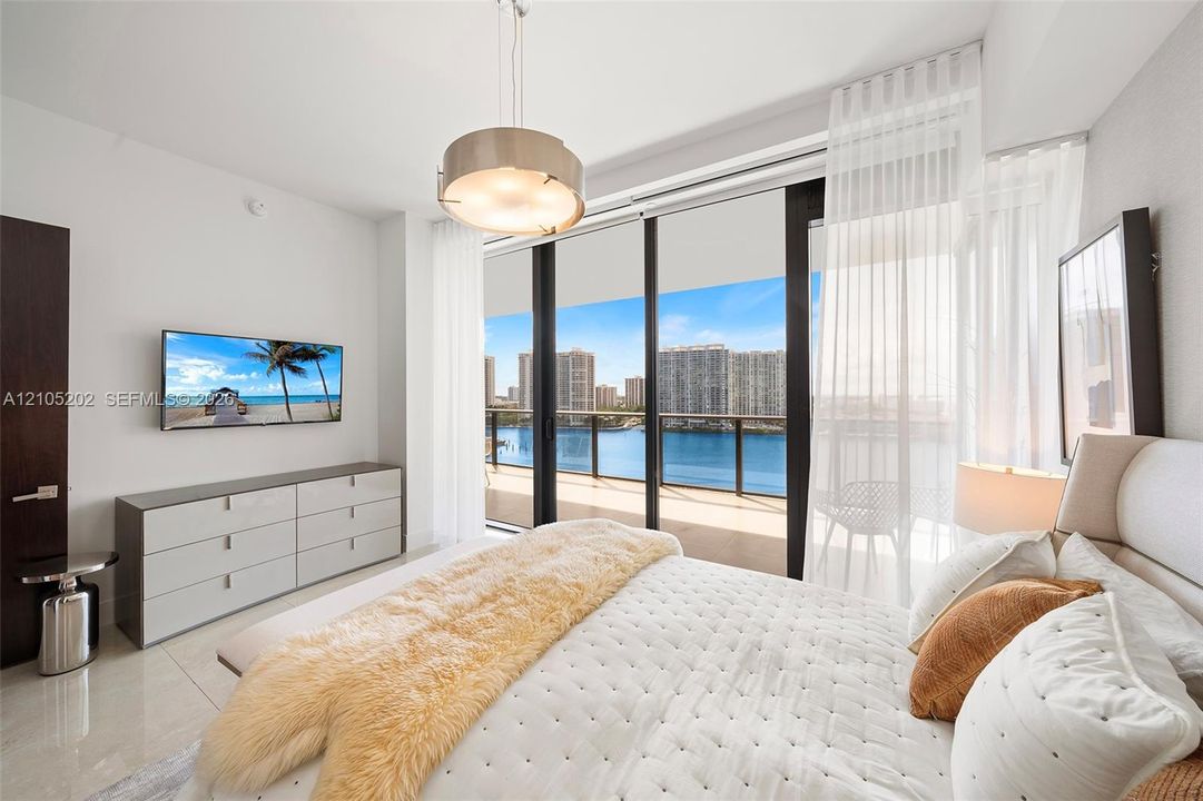 Floor-to-ceiling windows, sliding glass door with access to a private balcony, polished tile flooring, contemporary drum pendant lighting, and a neutral color palette