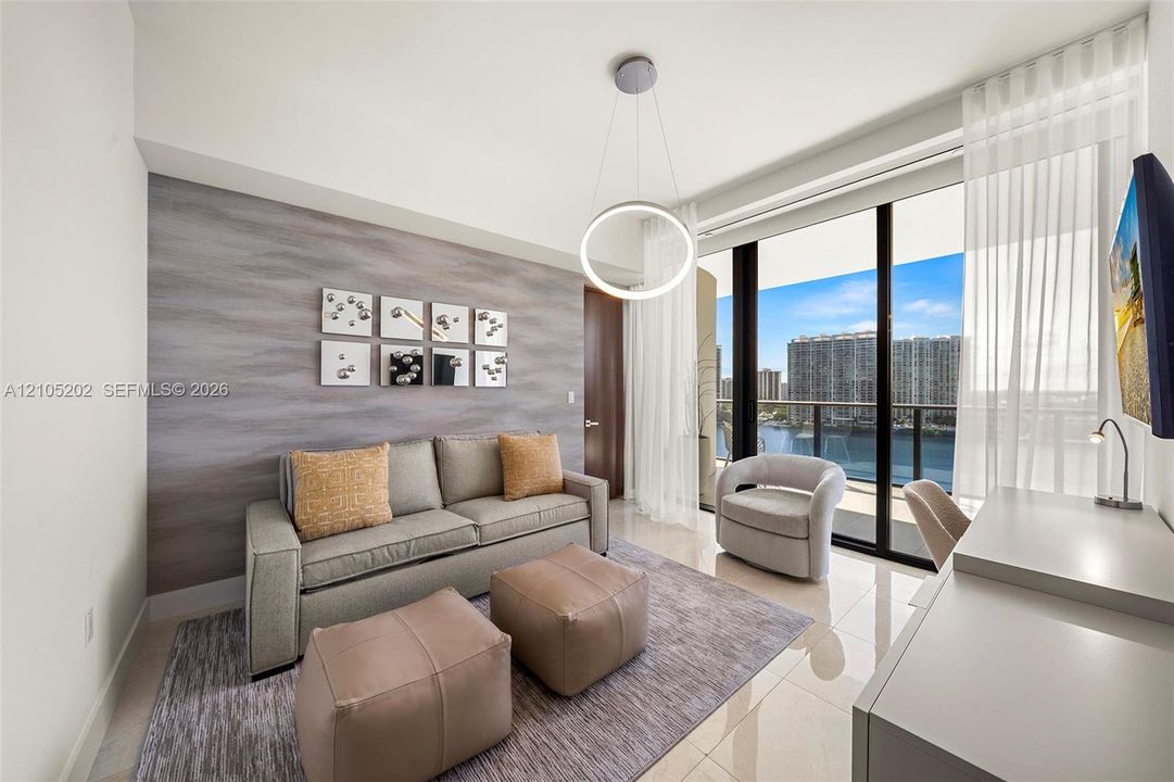 Floor-to-ceiling glass sliding doors, polished tile flooring, textured feature wall, circular contemporary pendant light, and attached private balcony
