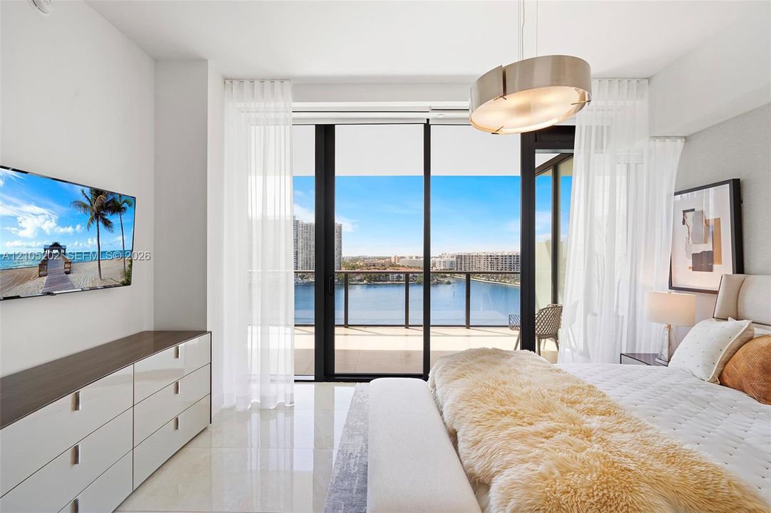 Floor-to-ceiling glass sliding doors, private balcony with metal railing, high-gloss tile flooring, built-in dual-toned cabinetry, and modern drum pendant lighting