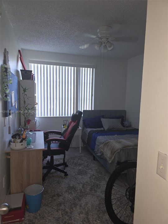 Room featuring a ceiling fan with integrated lighting and a large window with vertical blinds
