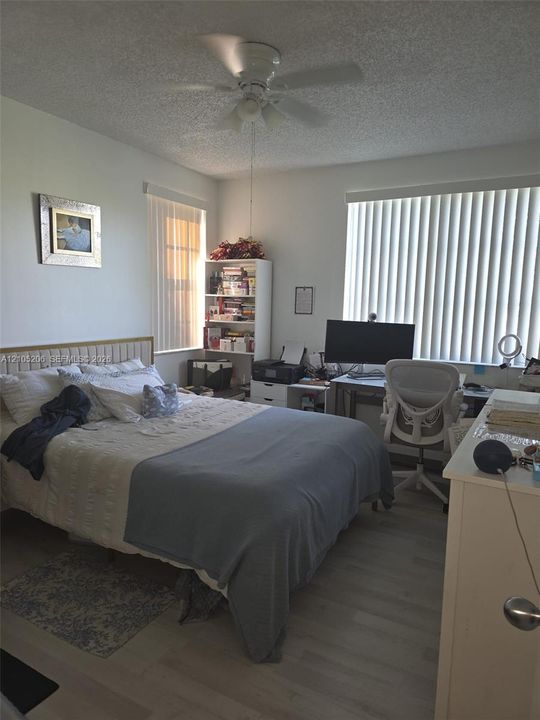 Room featuring light wood-finish flooring, white vertical window blinds, and a white ceiling fan with integrated lighting