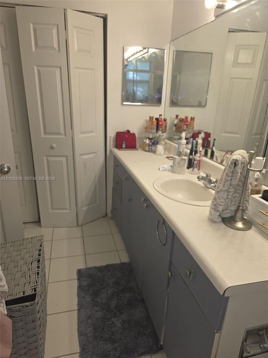 Extended vanity featuring a smooth surface countertop, integrated sink basin, and neutral-toned cabinetry with ring-pull hardware