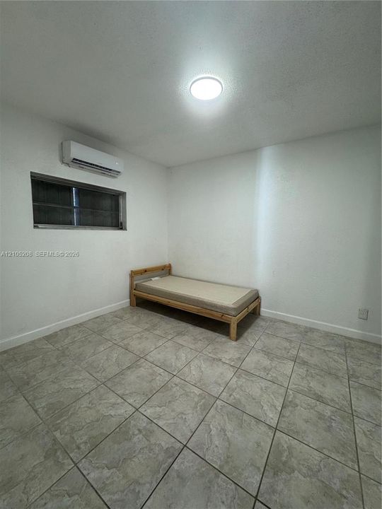 Recessed ceiling light, wall-mounted air conditioning unit, window, and tile flooring