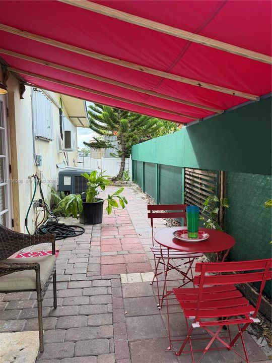Outdoor patio space featuring interlocking paver stones and a retractable fabric awning
