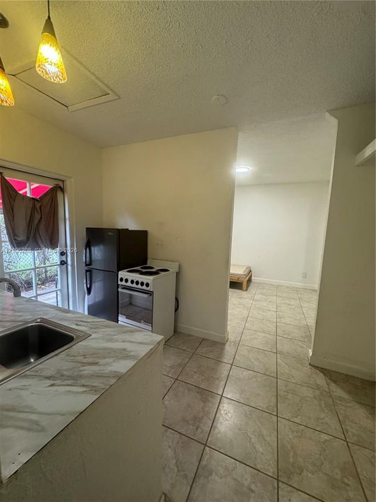 Kitchenette featuring a stainless steel sink, patterned countertop, and tile flooring