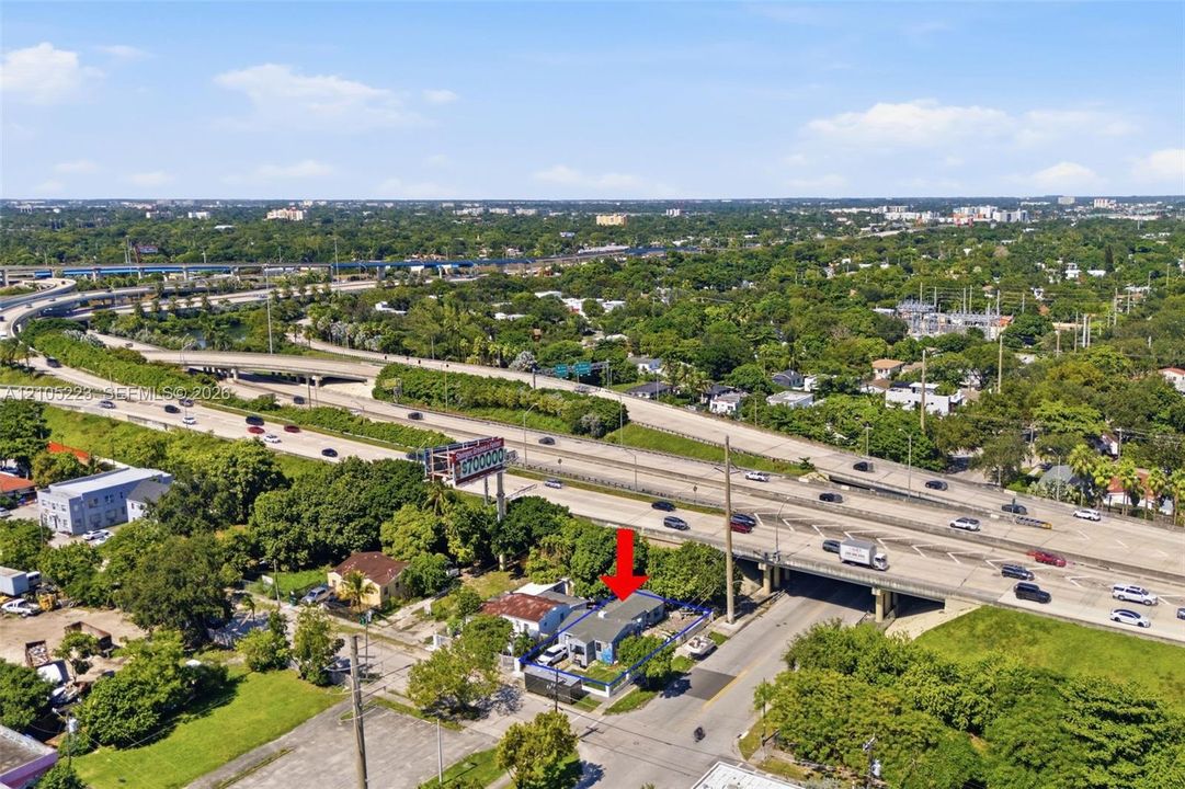 Aerial perspective of a detached single-story residence with a metal roof and perimeter fencing, situated on a corner lot