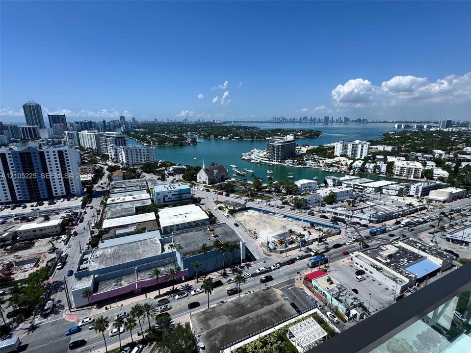Expansive cityscape and water scenery, featuring a prominent bay with boats, a church spire, and a distant skyline