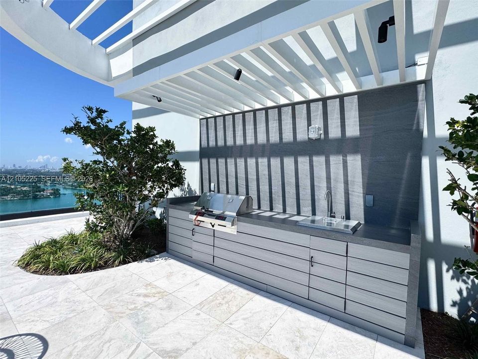 Outdoor kitchen featuring a built-in grill, integrated sink, and cabinetry