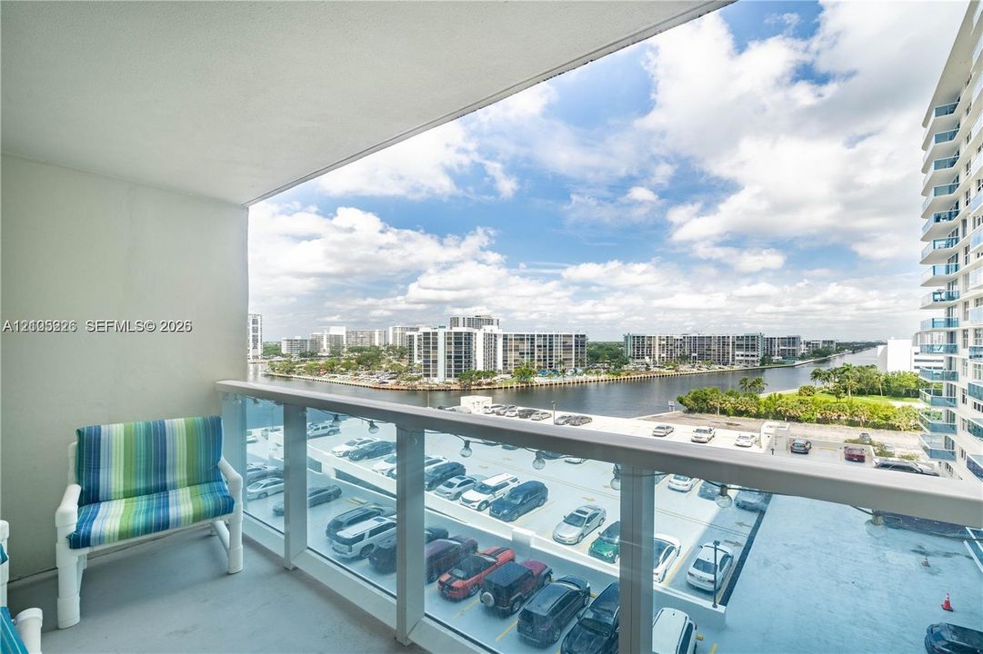 Covered balcony featuring glass pane railings and concrete flooring, overlooking the canal and surrounding cityscape