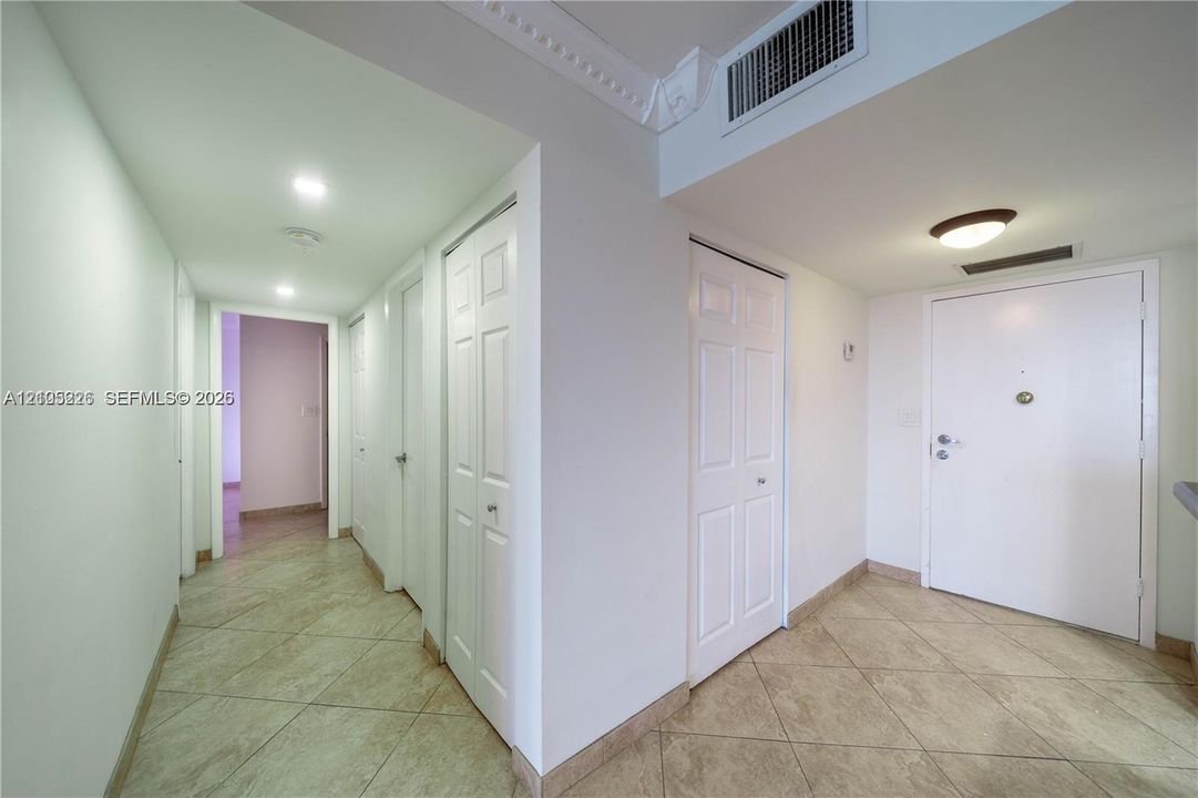 Entryway featuring light-toned tile flooring, crown molding, and multiple paneled interior doors