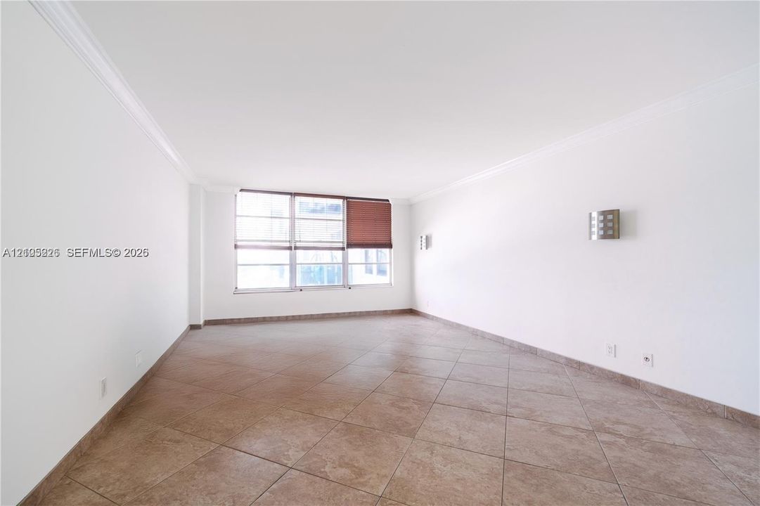 Open-concept interior featuring oversized tile flooring, crown molding, and expansive multi-pane windows with built-in wall-mounted light fixtures