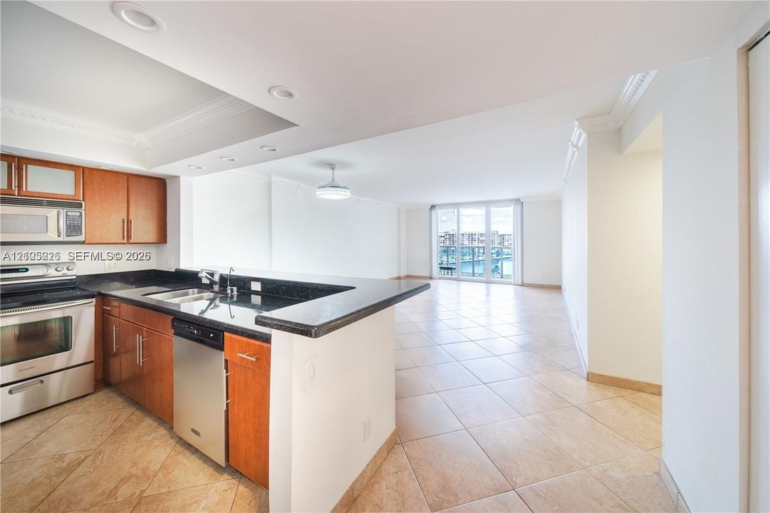 Kitchen featuring wood-finish cabinetry, stone-surface countertops, stainless steel appliances, tile flooring, and recessed lighting