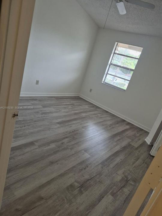 Room with neutral wall finish, wood-finish flooring, vaulted ceiling, ceiling fan, and window with horizontal blinds