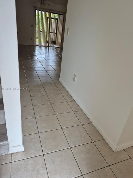 Ceramic tile flooring, neutral wall tones, and glass-paned sliding doors featuring vertical blinds