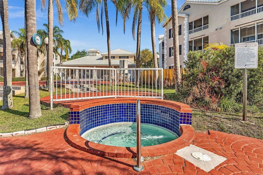 Spa with blue mosaic tile, surrounded by stamped brick-patterned hardscaping