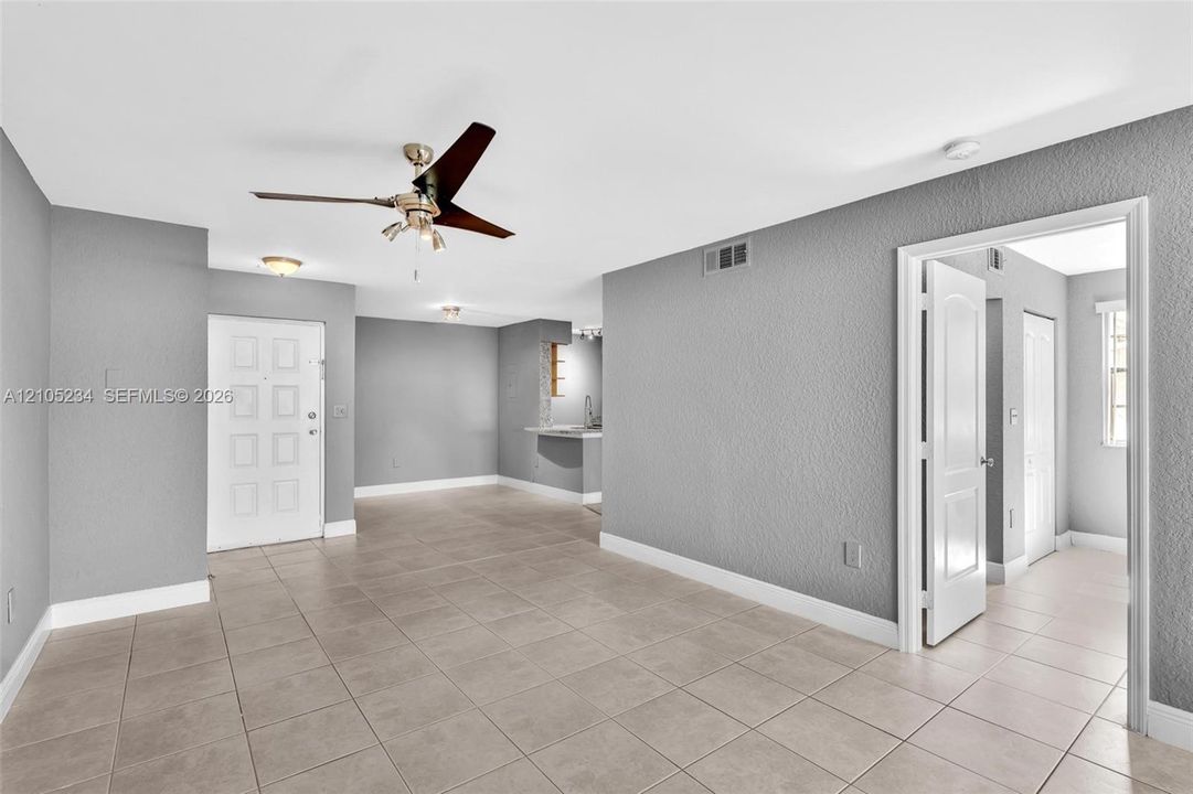 Spacious room featuring tile flooring, ceiling fan, white paneled door, and recessed lighting