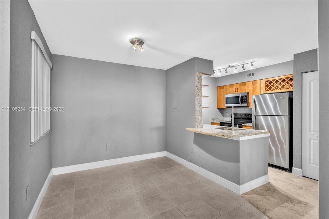 Kitchen featuring stainless steel appliances, wood cabinetry, built-in wine rack, and granite-style countertops with a breakfast bar
