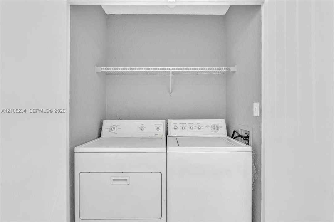 Dedicated laundry area featuring a washer, dryer, and wire shelving
