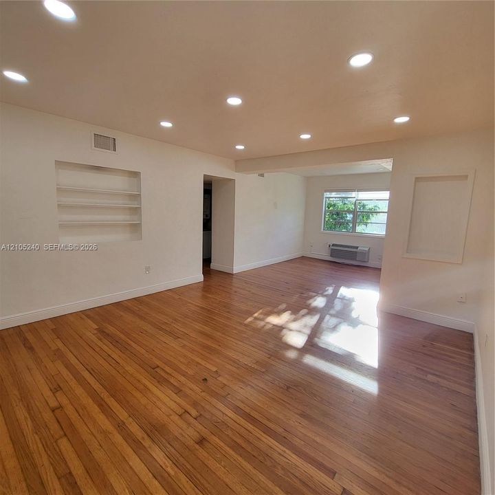 Hardwood flooring with recessed lighting, built-in wall shelving, and large windows