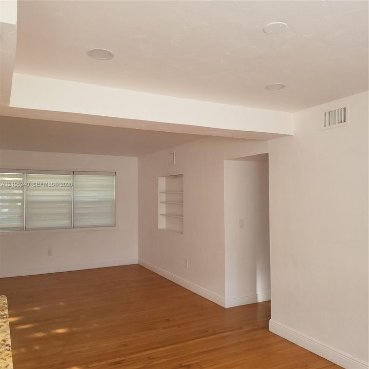 Recessed ceiling lighting, wood-finish flooring, built-in shelving, and large windows with blinds