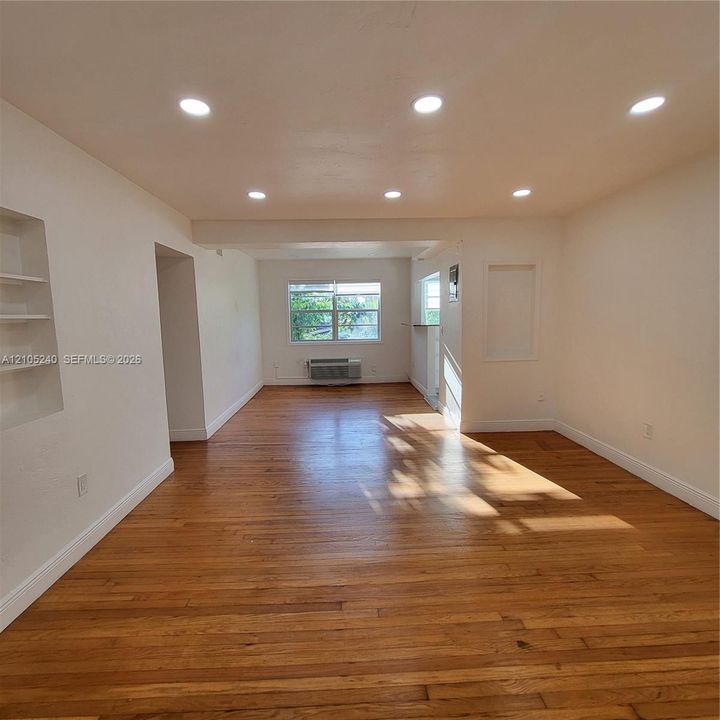 Hardwood flooring, recessed ceiling lighting, built-in shelving, and a bright window with exterior scenery