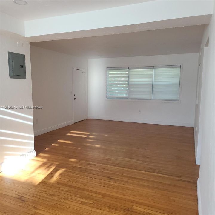Hardwood flooring, white walls, and a window with horizontal blinds