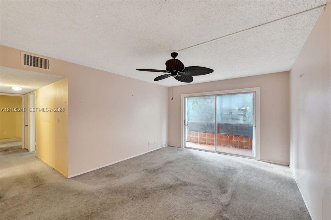 Interior space featuring sliding glass doors to a balcony, a ceiling-mounted fan, and carpeted flooring
