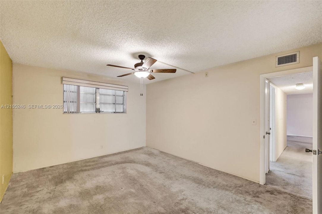 Room featuring wall-to-wall carpeting, a ceiling fan with integrated lighting, and a multi-pane horizontal window