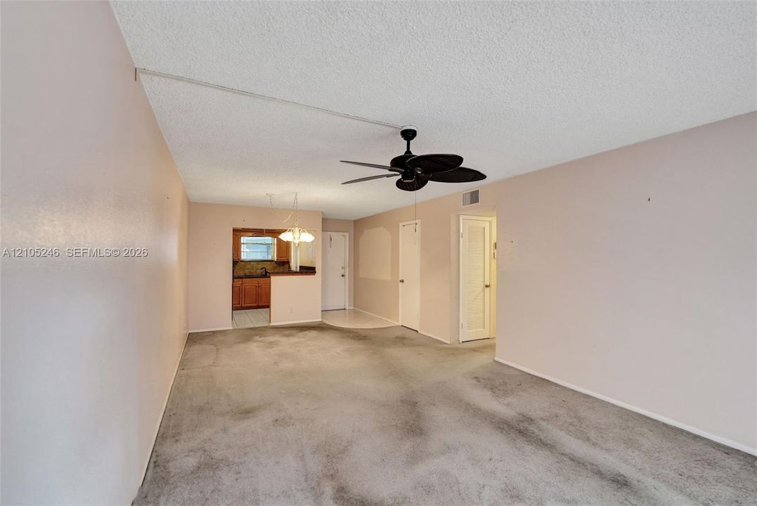 Living area featuring a ceiling fan with integrated lighting, neutral wall paint, and interior doors