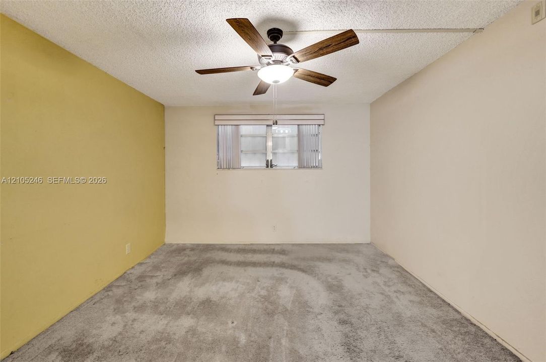 Room featuring carpeting, a ceiling fan with integrated lighting, and a window with horizontal blinds