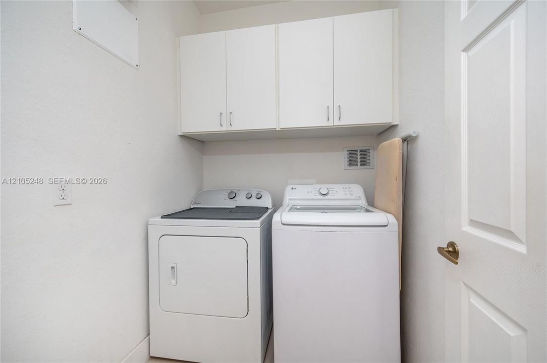 White upper cabinetry, white textured walls, and a white paneled door